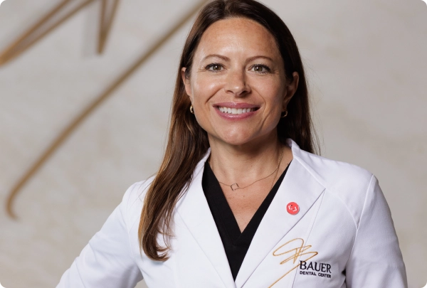 Dr. Viorela Bauer, smiling in a Bauer Dental Center lab coat.